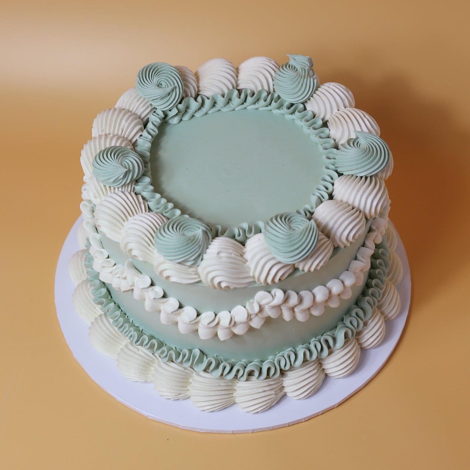 A birthday cake with green and white icing, decorated with a vintage design.