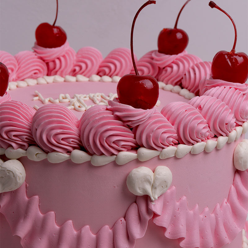 Pink vintage birthday cake with cherries on a light gray background