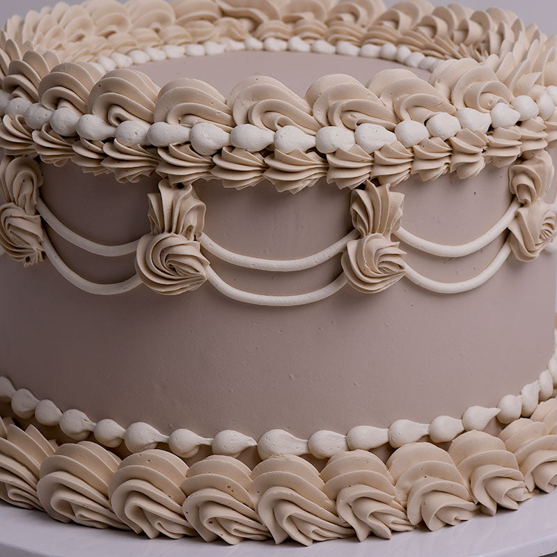 Close-up of a cake with vintage piping design in nude and beige tone