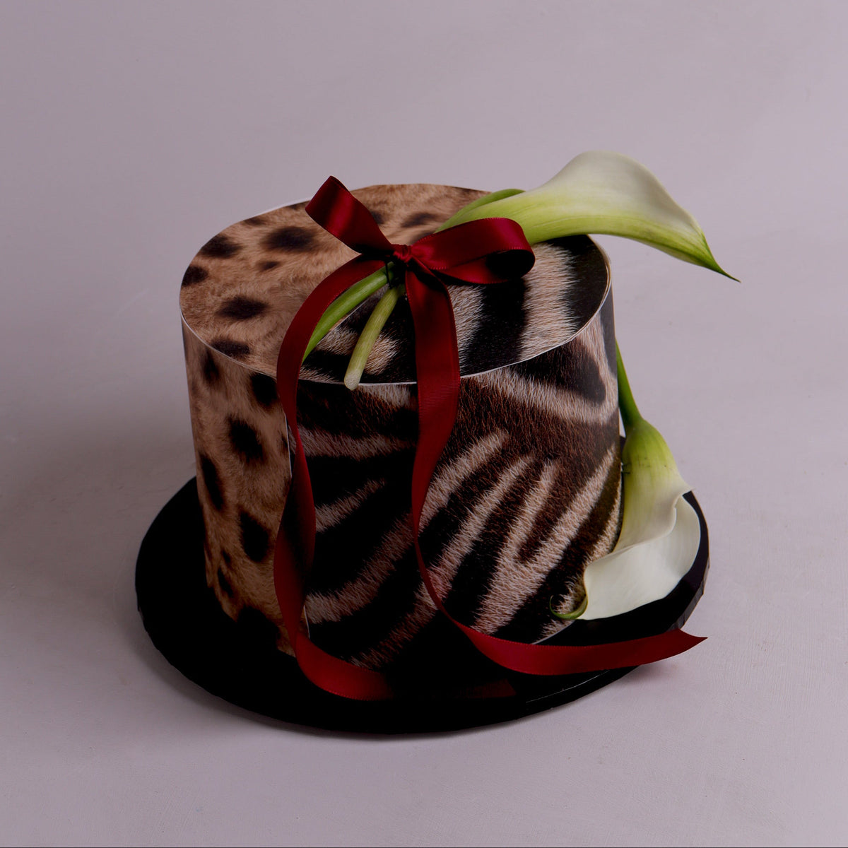 two tone animal print cake with fresh calla lilly and ribbon.