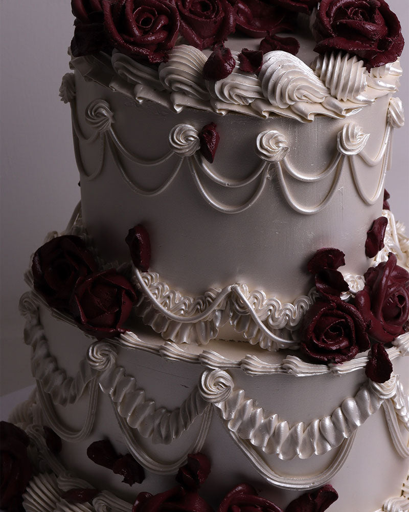 white vintage cake with burgundy buttercream roses for a wedding or birthday.