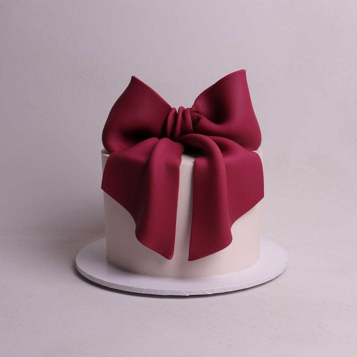 oversized burgundy fondant bow sitting on buttercream cake for birthday and baby shower events in Mellbourne. 