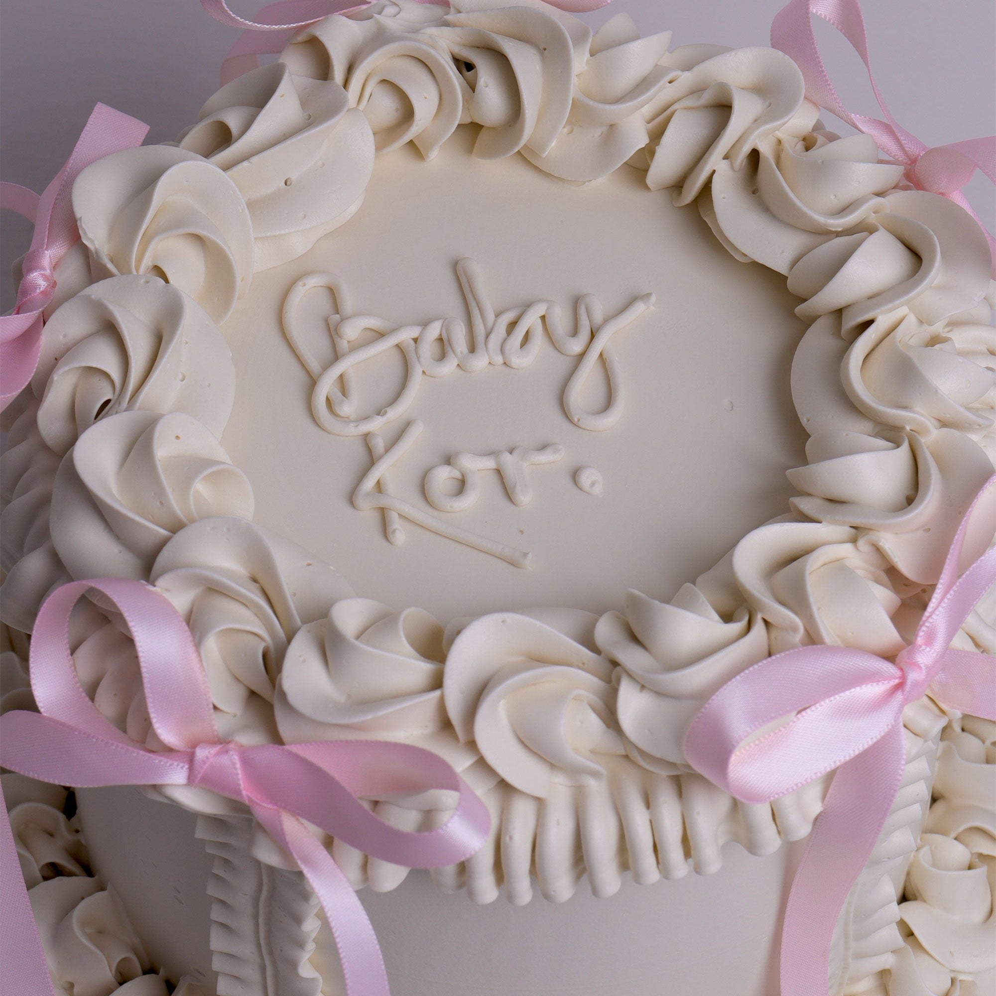 Vintage buttercream cake with pink ribbon bows and piped swirls