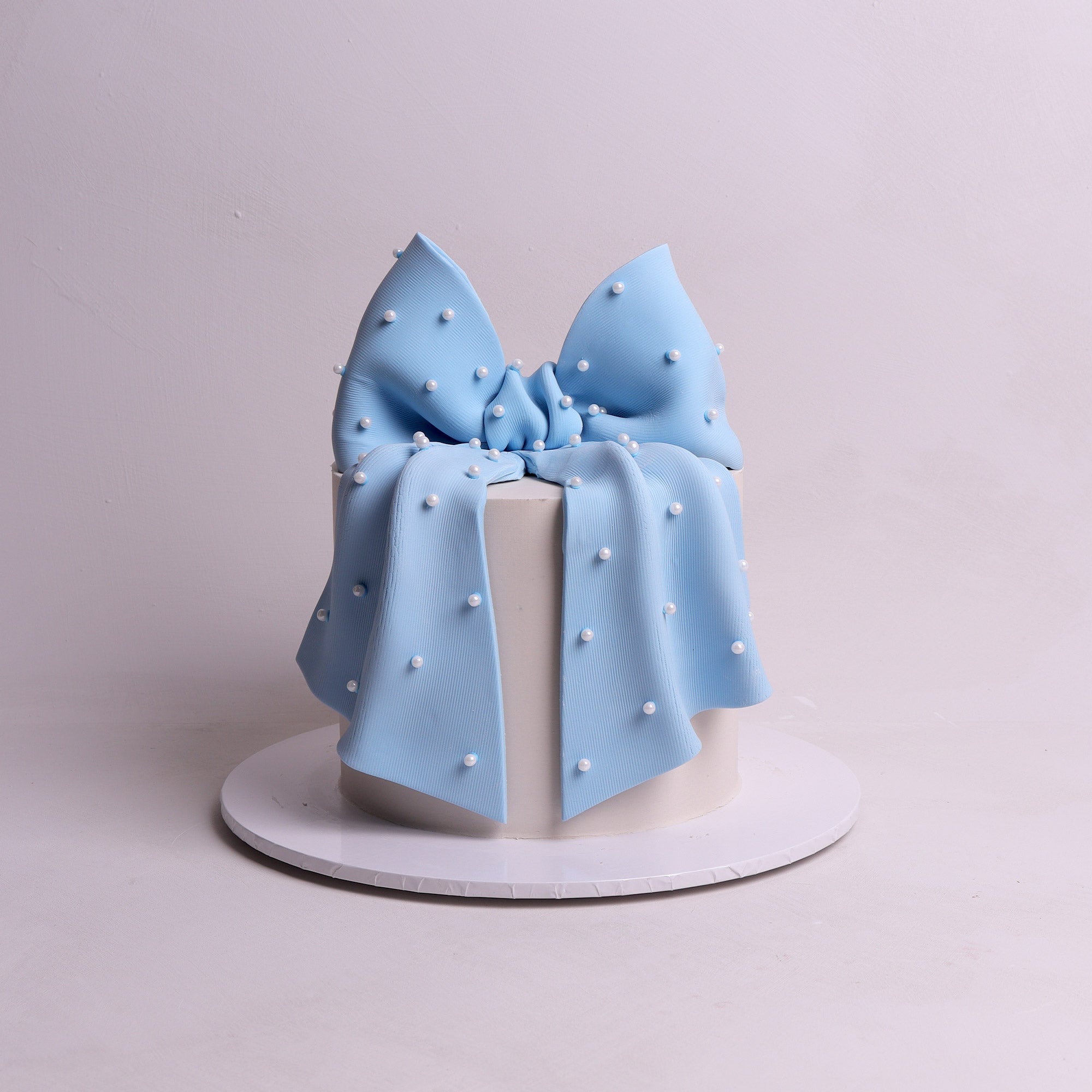 bow-shaped cake with pearl details for baby shower or bridal party events. 
