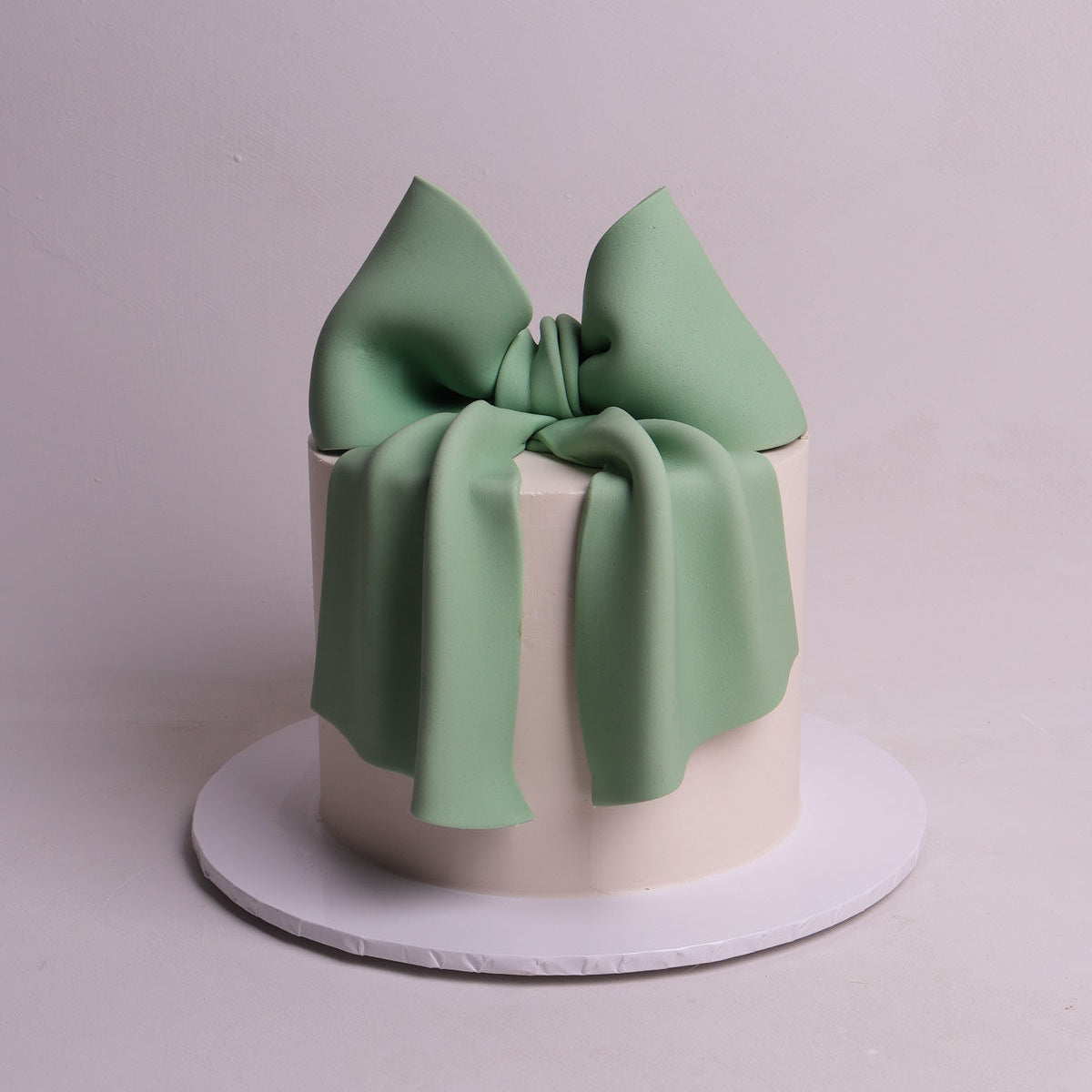 oversized sage green fondant bow sitting on buttercream cake for birthday and baby shower events in Mellbourne. 